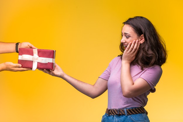 Young girl taking a gift box from her friend and smiling positively. Free Photo